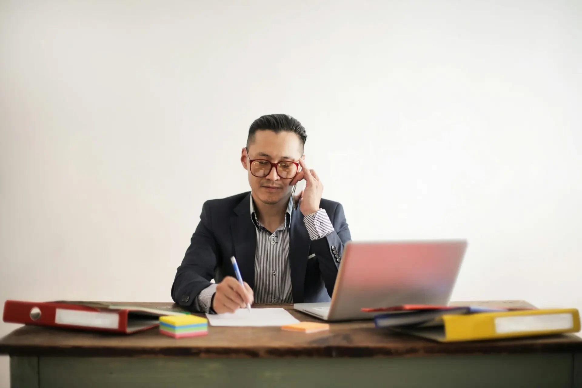 Business consultant on call taking notes at desk